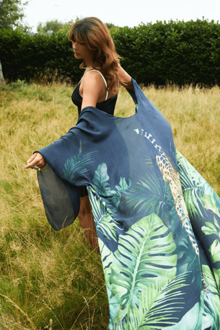 Woman holding a blue tropical patterned garment in a field