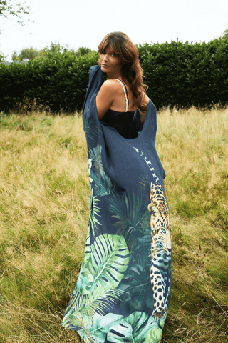 Woman holding a blue and green patterned scarf in a grassy field